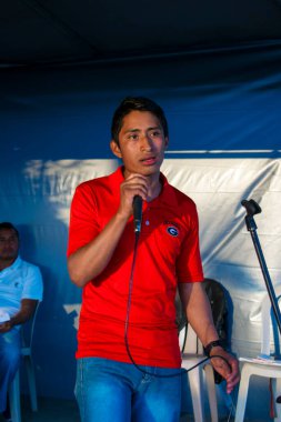 Gri arka planda şarkı söyleyen genç adam Cajola 'da sahnede mutlu.