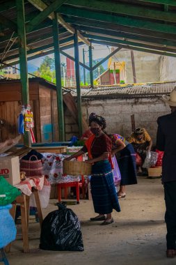 Kadınlar ellerinde tipik Maya giysileri sepetleriyle çarşıda salgın hastalığın ortasında alışveriş yapıyorlar.