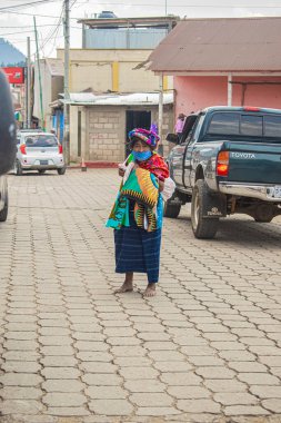 Kafasında sepet olan bir kadın ve tipik Maya kıyafetleri ile salgın hastalığın ortasında markette yürüyordu.