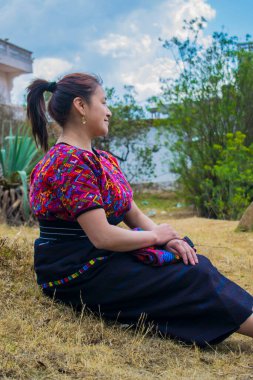 Nehrin kıyısında, siyah kesimli ve renkli huipil 'li bir kadın profilini araştırıyor.