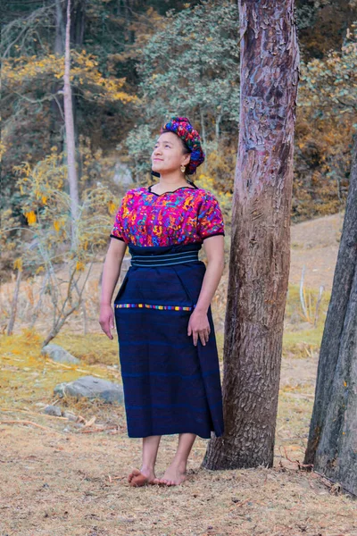 Güzel bir kadın renkli Maya kostümüyle ormanın ortasına bakıyor.