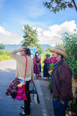 Şapkalı, tipik ahlaklı adamlar sokakta dikiliyorlar. Arka planda ağaçlar var.