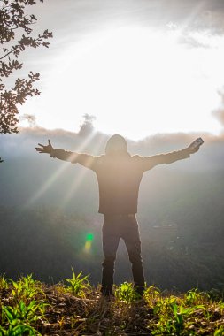 Geniş elleri olan, güneşli, ışıl ışıl, güzel manzaralı genç bir adam.