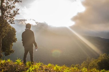 Elinde konserve kutusuyla duran genç adam siyah elbiseler giyerek güneşli güzel.