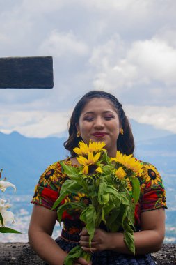 Elinde çiçekler, beyaz bulutlar ve dağınık saçlarla bir kadın.
