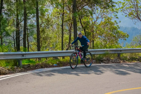 Ormanın ortasında siyah elbiseli bisikletli bir adam.