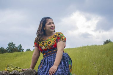 Bulutlu arka planı olan bir kadın profilde oturuyor.