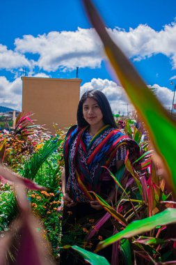 Uzun saçlı, mavi boyunlu, bulutlu gülümseyen kadın.