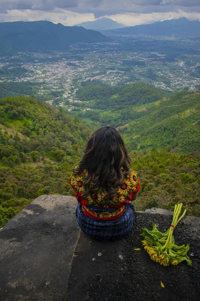 美丽的女人坐在岩石上 穿着艳丽多彩的衣服 背景是山谷 — 图库照片