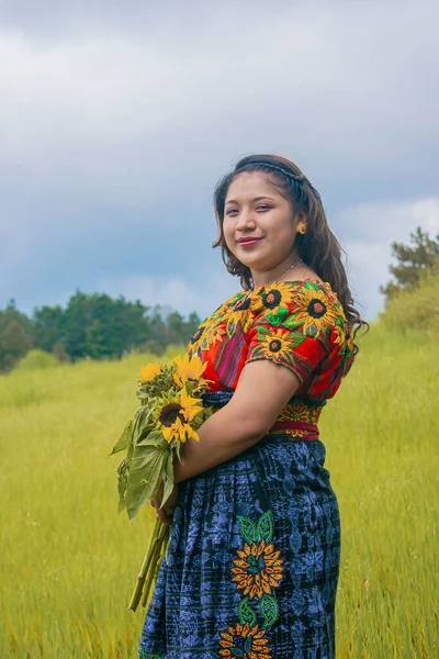 背景の雲と乾いた草を手に花を持つ美しい女性 — ストック写真