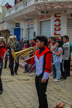 Caddenin kenarında duran kadınlar, park halindeki arabalı tipik Maya kıyafetleriyle...