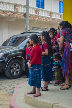 Caddenin kenarında duran kadınlar, park halindeki arabalı tipik Maya kıyafetleriyle...