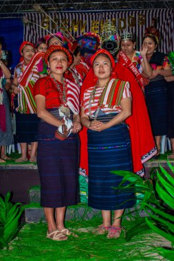 Kadınlar sahnede tipik kostümlü insanlarla dururlar.