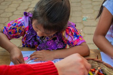 Tahta masa üzerinde renkli boya kalemleri olan güzel yerli bir kız.