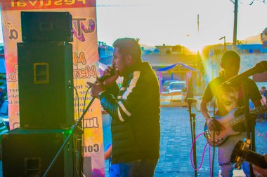 Siyah giyinmiş genç adam güneşli şarkılar söylüyor.