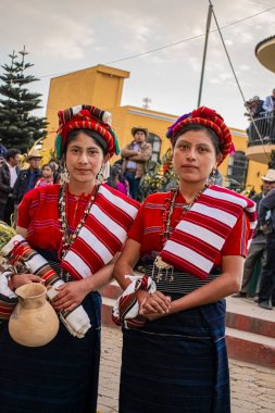 Arka planda insanlar olan cajola kostümlü iki yerli Maya kadını.