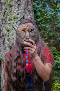 Orman geçmişi olan güzel bir kadın ve arkasında ağaç var.