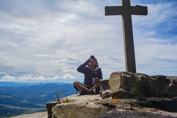 Junger Mann Sitzt Mit Kreuz Davor Und Blauen Wolken — Stockfoto