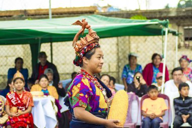 Kadın tipik Maya kostümü ve elinde mısır koçanıyla dans ediyor.