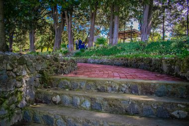 Arka planda ağaçlar olan tuğla ve kırmızı tribünler.