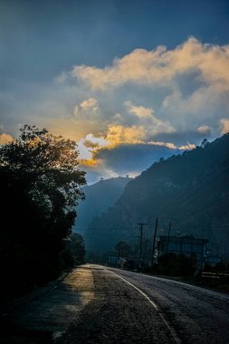 bulutlar ve yol arasında ışık olan dağların güzel manzarası