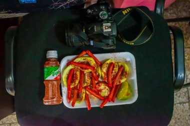 Kırmızı biberli beyaz tabakta mango ve kamera.