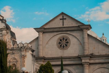 Gri renk ve gökyüzü arkaplanı önünde haç olan kilise cephesi