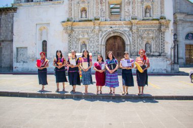Kitapları ellerinde ve tipik kıyafetleriyle yerli kadınlar.