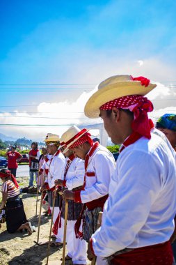 Renkli geleneksel kostümlü ve arkasında mavi gökyüzü olan adamlar.