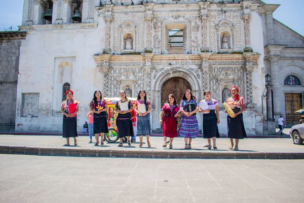 Arka planda kilise olan tipik Maya kostümüyle yürüyen güzel yerli kadınlar.