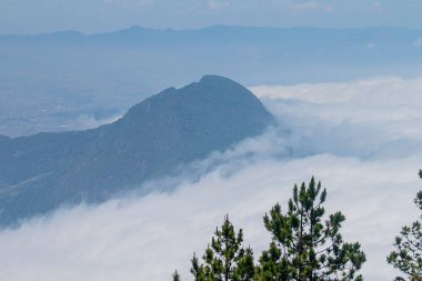Mavi gökyüzü manzaralı beyaz bulutların arasındaki tepeler.