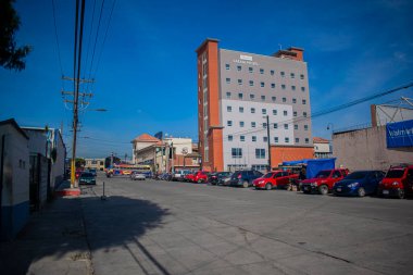 Arabaları ve mavi gökyüzü olan latam binası ve oteli.