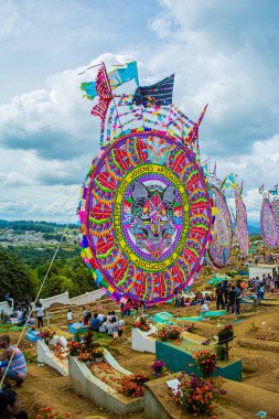 Gökyüzünde bulutlar ve bir sürü insanla mezarlıkta büyük bir Çin kağıt uçurtması.