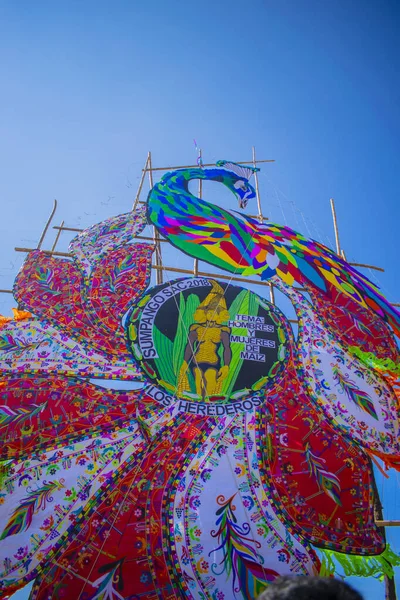 Büyük renkli uçurtmalar mavi gökyüzü ve kabile figürleri.