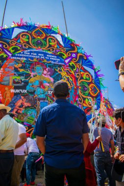 Genç adam Maya figürlü renkli uçurtmaya bakıyor.