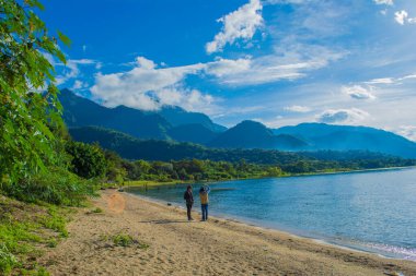Genç insanlar göl kıyısında dikiliyorlar.