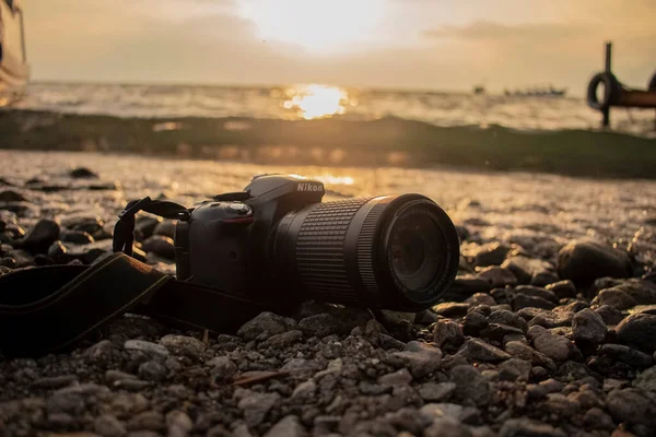 夕日を背景にした湖畔の黒いカメラ — ストック写真