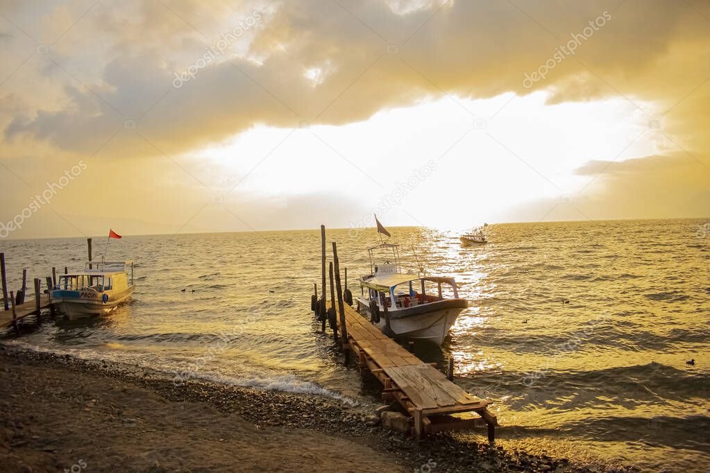 sunset with yellow clouds with pier and boat