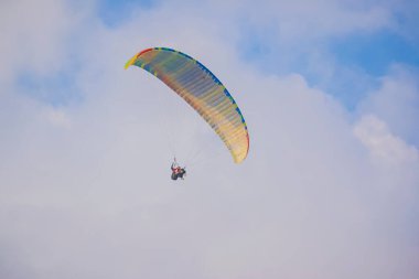 Mavi gökyüzü ile güzel renkli bulutlar arasında paraşütçü