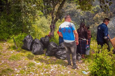 Genç insanlar ormanda ağaçlarla dolu bir bluz çantasıyla