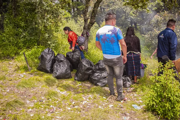 Gençler orman çantasından çöp topluyor.