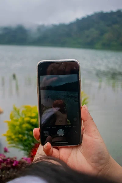 带有背景湖和森林的黑色手机 — 图库照片