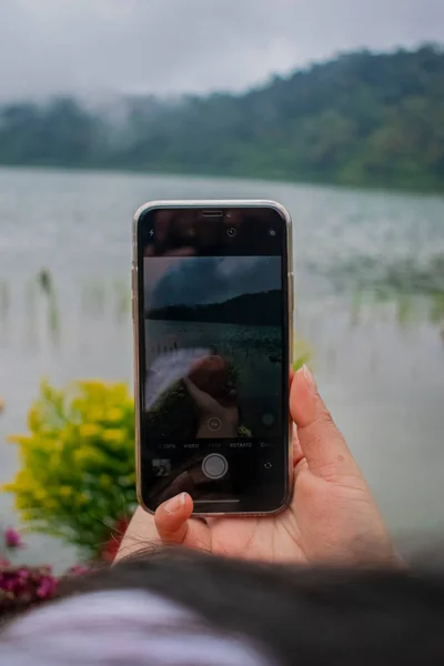 背景为湖的黑手电话 — 图库照片