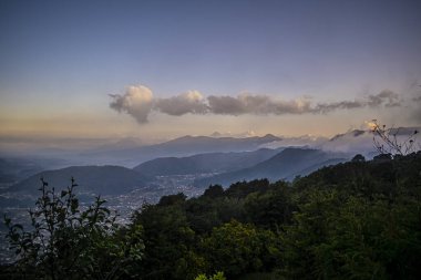 Altında kırmızı bulutlar olan şehirli dağlar