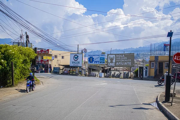 Yol kenarında işaretleri olan, gökyüzünde bulutları olan boş bir cadde.