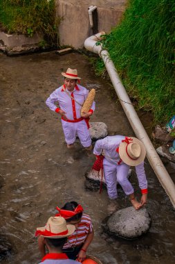 Tipik Maya kıyafetleriyle nehirde yürüyen iki adam.
