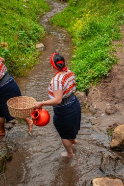 Maya kadını San Juan Ostuncalco 'dan kıyafetlerle nehirde yürüyor.