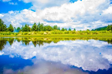 Arka planda ağaçlarla dolu güzel bir vadi. Etrafında insanların yürüdüğü büyük bir göl.