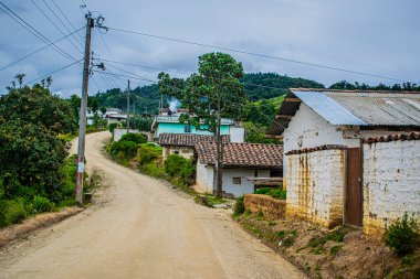 Arka planda güzel bir manzara, caddenin kenarında eski bir kerpiç evi