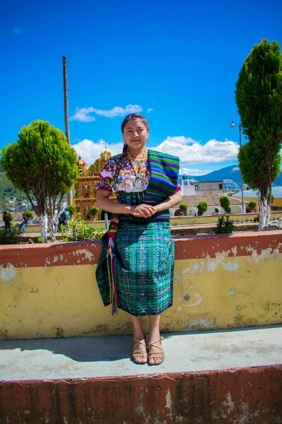 Maya hanımı, parkta oturuyor, tipik güzel kostümü, yeşil ve arkasında güzel bir manzara.